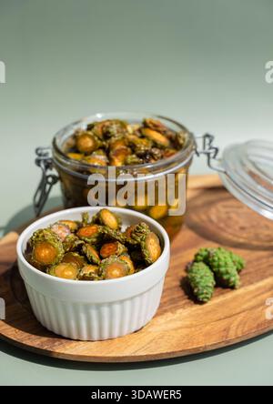 Primo piano di miele di cono di pino biologico in un recipiente di ceramica bianca e vaso di vetro trasparente su un vassoio di legno Lo sfondo verde naturale migliora il rustico p Foto Stock