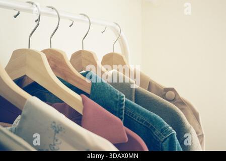 Vista ravvicinata di una fila di camicie su appendiabiti in legno. Foto Stock