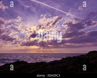 Nuvole al tramonto sull'oceano scuro e sulla costa rocciosa Foto Stock