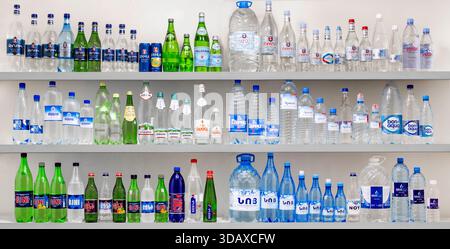 Erevan Armenia 12.5,2025. Un ripiano pieno di bottiglie d'acqua con colori e design diversi. Le bottiglie sono disposte in file, con alcune bottiglie Foto Stock