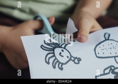 Bambino impegnato nel taglio dettagliato della carta durante la sessione artigianale Foto Stock