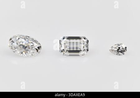 Tre diamanti bianchi di forma diversa sono visualizzati su uno sfondo bianco. I diamanti sono di forme e dimensioni diverse, con uno di diametro rotondo Foto Stock