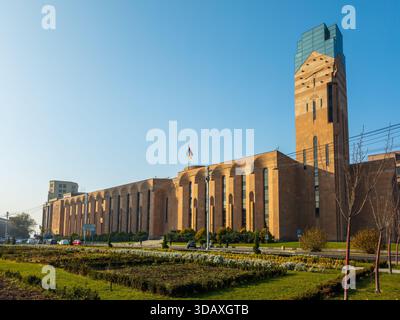 Erevan Armenia 12.5,2025. Un grande edificio di municipio con una bandiera sopra di esso. L'edificio è marrone e ha molte finestre Foto Stock