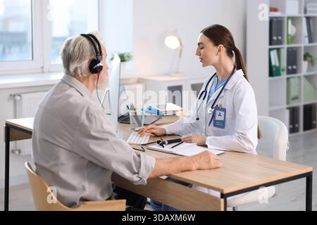 Paziente con cuffie audiometriche sottoposto a test uditivo in clinica Foto Stock