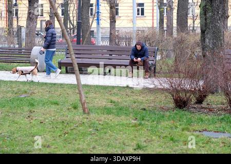 Due persone si godono una passeggiata e una pausa tranquilla in un tranquillo parco verde. Kiev, Ucraina. 12 dicembre 2025. Foto Stock