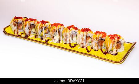 Sushi da buongustai ripieni di salmone, avocado e riso, conditi con salse e uova di pesce, serviti su un piatto rettangolare di ceramica isolato su bianco. Foto Stock