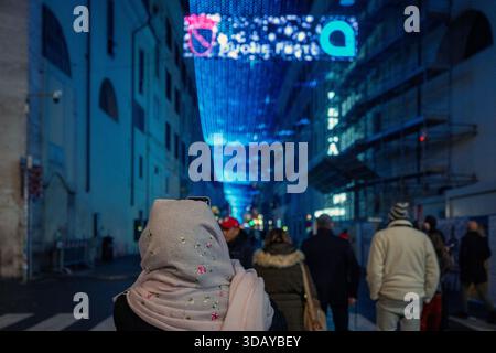 Roma, Italia - 8 dicembre 2025: Una donna che indossa un hijab scatta foto delle nuove luci natalizie in via del corso, nel centro storico del Capit Foto Stock