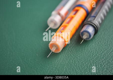 Diversi tipi di penne per insulina su una superficie verde Foto Stock