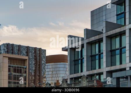 Vari stili architettonici si fondono in un ambiente urbano, caratterizzato da moderne facciate in vetro e pannelli e da ornati dettagli storici dell'edificio sotto a. Foto Stock