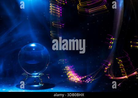 Scena mistica astratta con una sfera di cristallo usata nei rituali di divinazione e visione futura, circondata da colorate piste di luce che simboleggiano Foto Stock