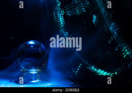 Scena mistica astratta con una sfera di cristallo usata nei rituali di divinazione e visione futura, circondata da colorate piste di luce che simboleggiano Foto Stock