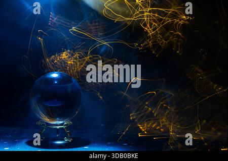 Scena mistica astratta con una sfera di cristallo usata nei rituali di divinazione e visione futura, circondata da colorate piste di luce che simboleggiano Foto Stock