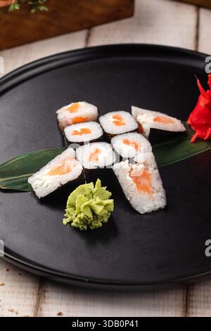 Sushi al maki di salmone su piatto nero Foto Stock