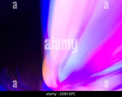 I toni al neon brillanti scorrono attraverso sfumature uniformi con un movimento sfocato. Movimento astratto della luce colorata. Foto Stock