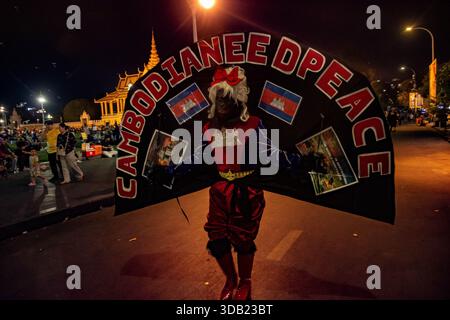 Phnom Penh, Phnom Penh, Cambogia. 13 dicembre 2025. Sisowath Quay, Phnom Penh, Cambogia. Un trans-attivista indossa un costume dicendo: La Cambogia ha bisogno di pace. Sisowath Quay accanto al fiume Tonle SAP. Nelle serate del fine settimana il lungofiume è pedonale e attira un gran numero di amanti del divertimento nel fine settimana. Tuttavia il conflitto in corso con la Thailandia ha colpito questa settimana una nota più cupa. (Immagine di credito: © Rod Harbinson/ZUMA Press Wire) SOLO PER USO EDITORIALE! Non per USO commerciale! Foto Stock