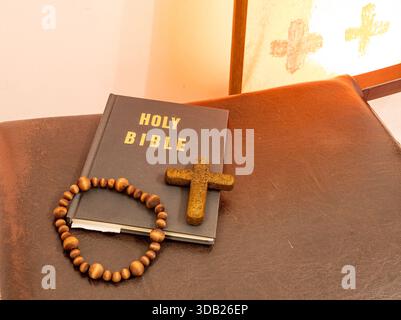 Perline del Rosario e croce crocifisso sulla Santa bibbia in chiesa Foto Stock