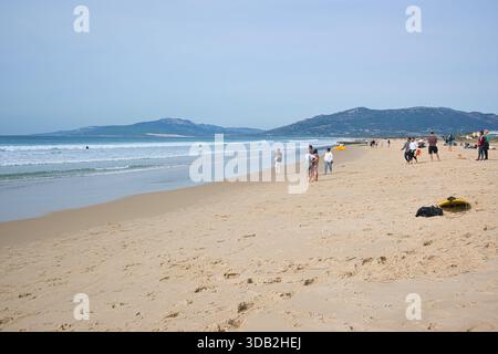 Tarifa, Spagna - 09 novembre 2025: Le persone camminano lungo la spiaggia sabbiosa di Tarifa vicino all'oceano. Foto Stock