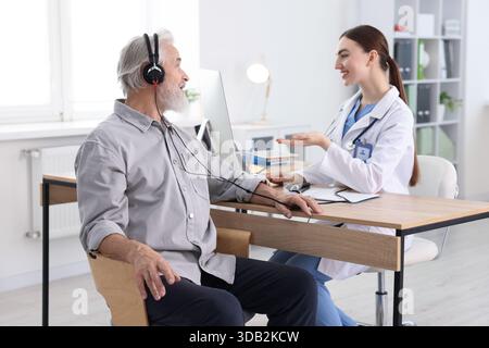 Paziente con cuffie audiometriche sottoposto a test uditivo in clinica Foto Stock