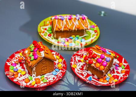 Vista ravvicinata delle colorate case di pan di zenzero decorate con caramelle per Natale su piatti. Svezia. Foto Stock