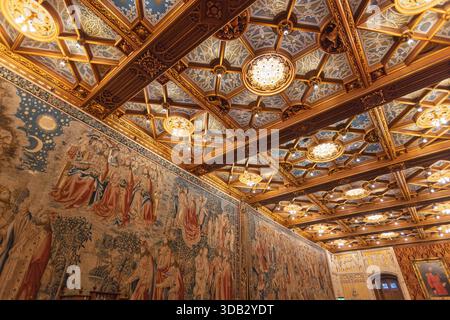 Soffitti ornati e arazzi a parete all'interno del Castello De Haar. Dettagliata architettura gotica revival con motivi dorati, blu e opere d'arte religiose. Haarzu Foto Stock