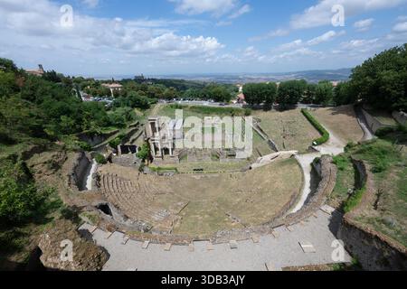Veduta aerea del Teatro Romano di Volterra del i secolo a.C., che mostra cavea semicircolare, resti di scena e colline toscane oltre. Foto Stock
