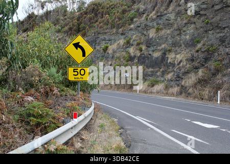 Great Ocean Road con cartello di limite di velocità che si snoda attraverso una montagna a Victoria, Australia Foto Stock