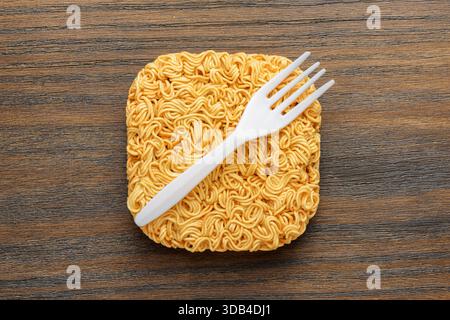Vista dall'alto degli spaghetti istantanei essiccati e della forchetta monouso bianca Foto Stock