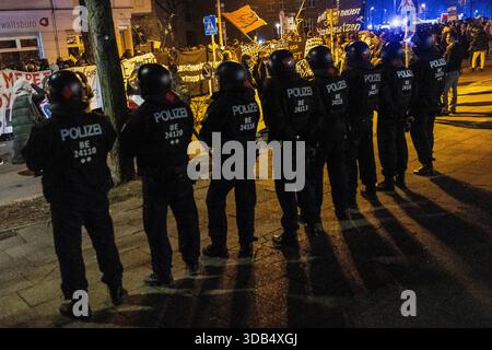 Gli agenti di polizia sono visibili in primo piano sullo sfondo di manifestanti durante una dimostrazione da parte di gruppi di sinistra contro la polizia nel distretto di Friedrichshain mentre la polizia protegge l'area. La manifestazione si è svolta durante l'annuale manifestazione anti-polizia a Friedrichshain (spesso indicato come ACAB Day) di Berlino. I partecipanti protestavano contro le pratiche di polizia e le forze dell'ordine in generale, e parte della manifestazione includeva anche slogan e messaggi filo-palestinesi. (Foto di Vasily Krestyaninov/SOPA Images/Sipa USA) Foto Stock