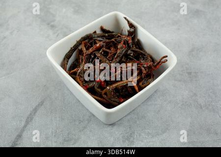 Una vista su una piccola ciotola quadrata di kimchi di dente di leone. Foto Stock