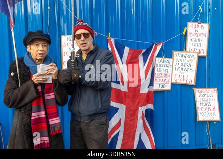 Londra, Regno Unito, 13 dicembre 2025, un uomo e una donna anziani stanno accanto a una bandiera union Jack, circondati da cartelli scritti a mano con messaggi politici, incl Foto Stock
