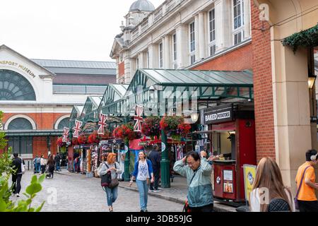 Londra, Inghilterra - 7 agosto 2025: Le persone passeggiano tra le bancarelle del mercato con esposizioni colorate e fiori luminosi. Foto Stock