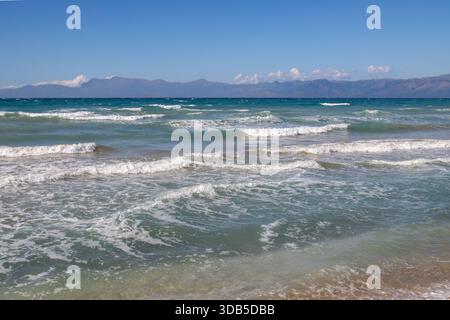 Mare Ionio con onde spettacolari durante una tarda giornata estiva. Montagne albanesi sullo sfondo. Cielo blu con nuvole bianche. A nord dell'isola di Corfù ( Foto Stock