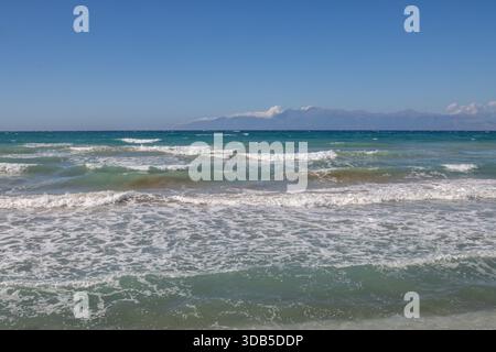 Mare Ionio con onde spettacolari durante una tarda giornata estiva. Montagne albanesi sullo sfondo. Cielo blu con nuvole bianche. A nord dell'isola di Corfù ( Foto Stock