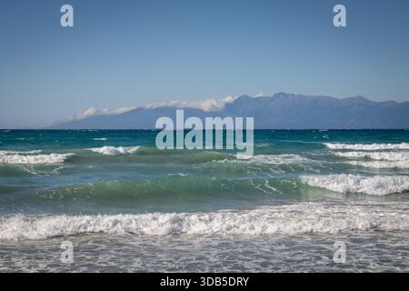 Mare Ionio con onde spettacolari durante una tarda giornata estiva. Montagne albanesi sullo sfondo. Cielo blu con nuvole bianche. A nord dell'isola di Corfù ( Foto Stock