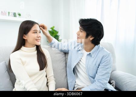 coppia sorridente e felice, marito aiuta a mettere i capelli per moglie, coccole, giovane amore, coppia sposata, famiglia calda. Marito e moglie innamorati così divertenti nel nuovo anno Foto Stock