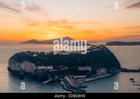 Edifici costieri al tramonto con montagne sullo sfondo. Nisida, Napoli Foto Stock