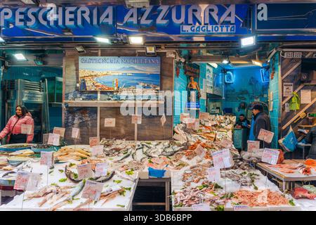 Napoli, 15 marzo 2024: Una donna sfoglia pesce fresco alla Pescheria Azzurra, un vivace mercato del pesce Foto Stock