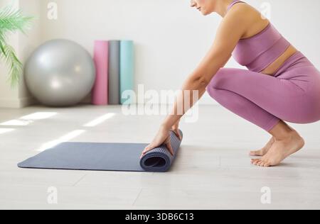 Indossate una giovane donna con un tappetino per lo yoga e preparatevi per una sessione di allenamento. Foto Stock