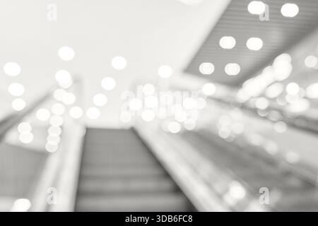 Immagine astratta sfocata di scala mobile con luci bokeh luminose nel moderno centro commerciale. Foto Stock
