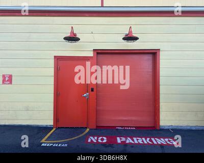 Nessun cartello di parcheggio verniciato a terra davanti alla porta industriale rossa Foto Stock