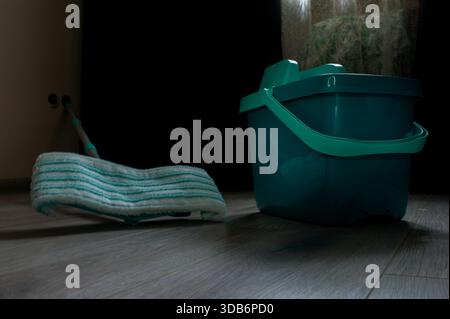 Attrezzature per la pulizia della casa in soggiorno. Uno spazzolone e un secchio vengono utilizzati come utensili per la pulizia domestica. Foto Stock