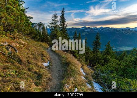 Una tranquilla escursione autunnale lungo un sentiero tortuoso nella valle del Tannheimer, che evoca tranquillità e avventura mentre gli escursionisti salgono verso la montagna mozzafiato Foto Stock