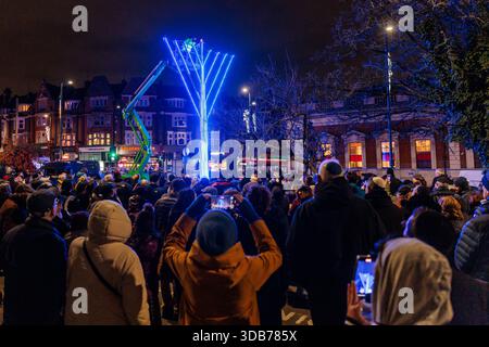 Golders Green, Londra, Regno Unito. 14 dicembre 2025. I membri della Golders Green Community illuminano la menorah pubblica Chabad. La prima candela fu accesa, segnando l'inizio di Hanukkah, la festa ebraica delle luci. L'evento si è tenuto sotto stretta sicurezza a seguito di un orribile attacco antisemita durante una celebrazione Hanukkah tenutasi oggi a Bondi Beach, in Australia, in cui sono state uccise almeno 12 persone. Crediti: Amanda Rose/Alamy Live News Foto Stock