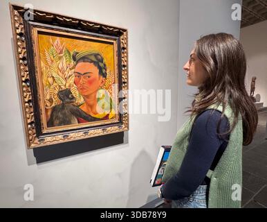 New York, New York, Stati Uniti. 13 dicembre 2025. A Woman Views ''˜Autorretrato con chango y loro,1942' di Frida Kahlo che ha venduto per $ 3.192.500 il 17 maggio 1995 visto durante l'anteprima stampa di ''˜Icons Back to Madison' la prima mostra di riferimento nel suo genere che riporta le opere precedentemente vendute da Sotheby's, tenutasi presso l'edificio Breuer. (Credit Image: © Nancy Kaszerman/ZUMA Press Wire) SOLO PER USO EDITORIALE! Non per USO commerciale! Foto Stock