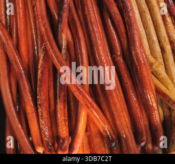 Primo piano di lunghe salsicce affumicate riscaldate sulla griglia al mercatino di Natale Foto Stock
