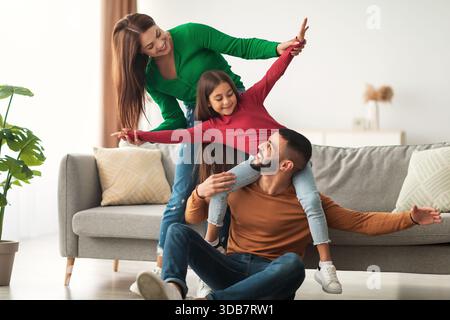 Famiglia araba felice che si diverte a trascorrere momenti ludici insieme nel loro salotto Foto Stock