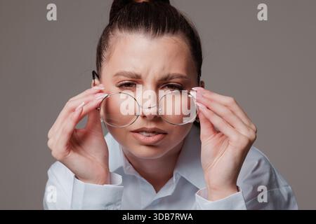 Primo piano di una donna con scarsa vista che cerca di focalizzare la vista dopo essersi tolta gli occhiali, Foto Stock