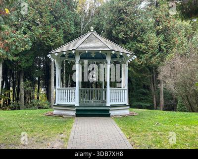 Gazebo di legno bianco in una radura della foresta in una giornata nuvolosa. Foto Stock