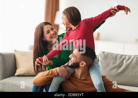 Famiglia araba felice che si diverte del tempo di qualità insieme a casa nel soggiorno Foto Stock