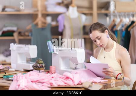 Una donna turbata che controlla alcuni documenti in un negozio di sartoria Foto Stock